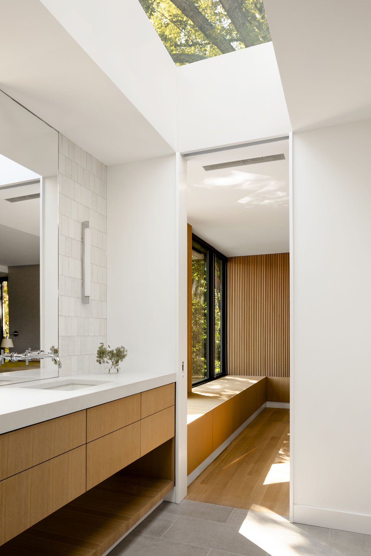 Renovated bathroom with large skylight and warm wood cabinetry