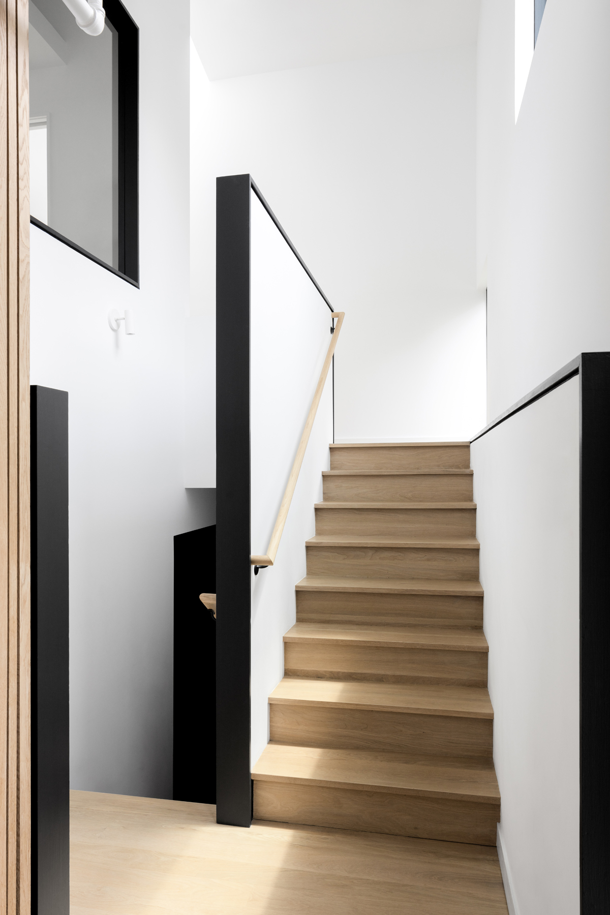 Simple stair with black trim and playful windows and light